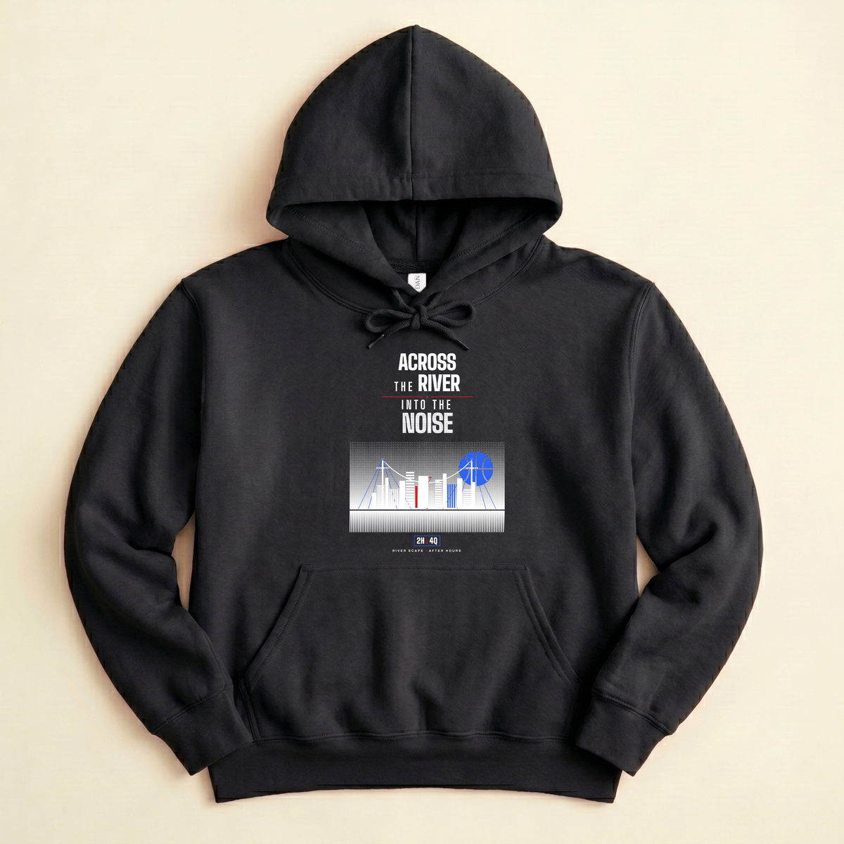 A black pullover hoodie laid flat on a light beige background, featuring a front graphic with the text 'ACROSS THE RIVER INTO THE NOISE' above a blue-toned city skyline illustration with blue basketball shaped moon, laid flat on a warm beige background.