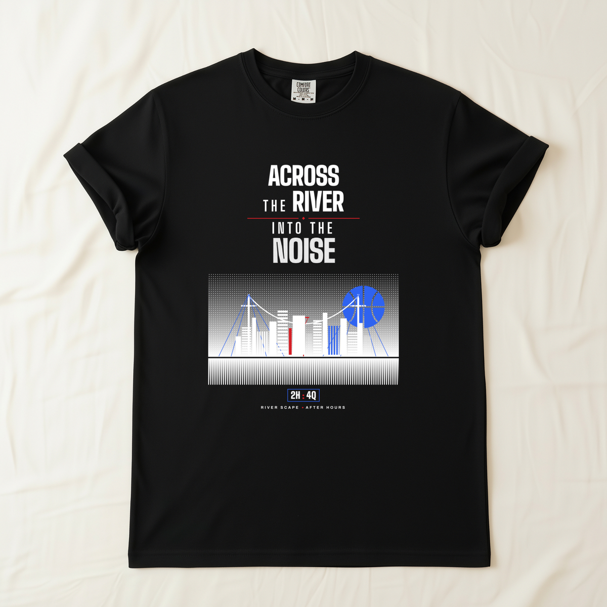 A black short-sleeve graphic t-shirt laid flat on a light beige fabric background. The shirt features a white and blue graphic print with the text 'ACROSS THE RIVER INTO THE NOISE' and a stylized city skyline illustration with blue basketball shaped moon. 