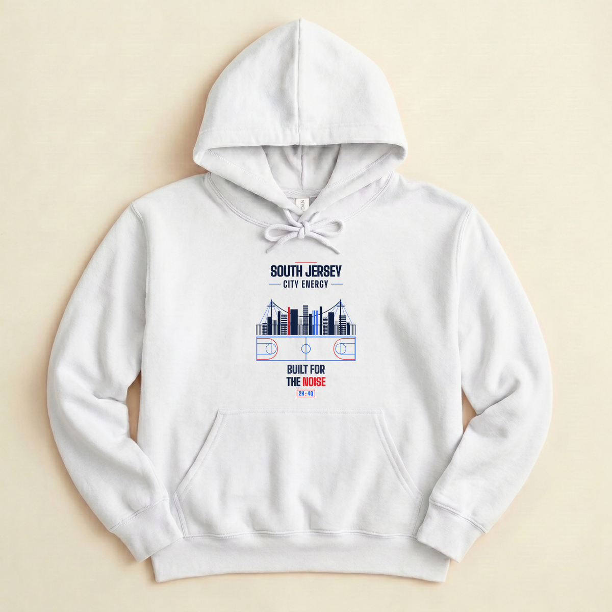 A white pullover hoodie laid flat on a light beige background, featuring a front graphic with the text 'SOUTH JERSEY CITY ENERGY' and 'BUILT FOR THE NOISE' around a stylized basketball court and skyline design.