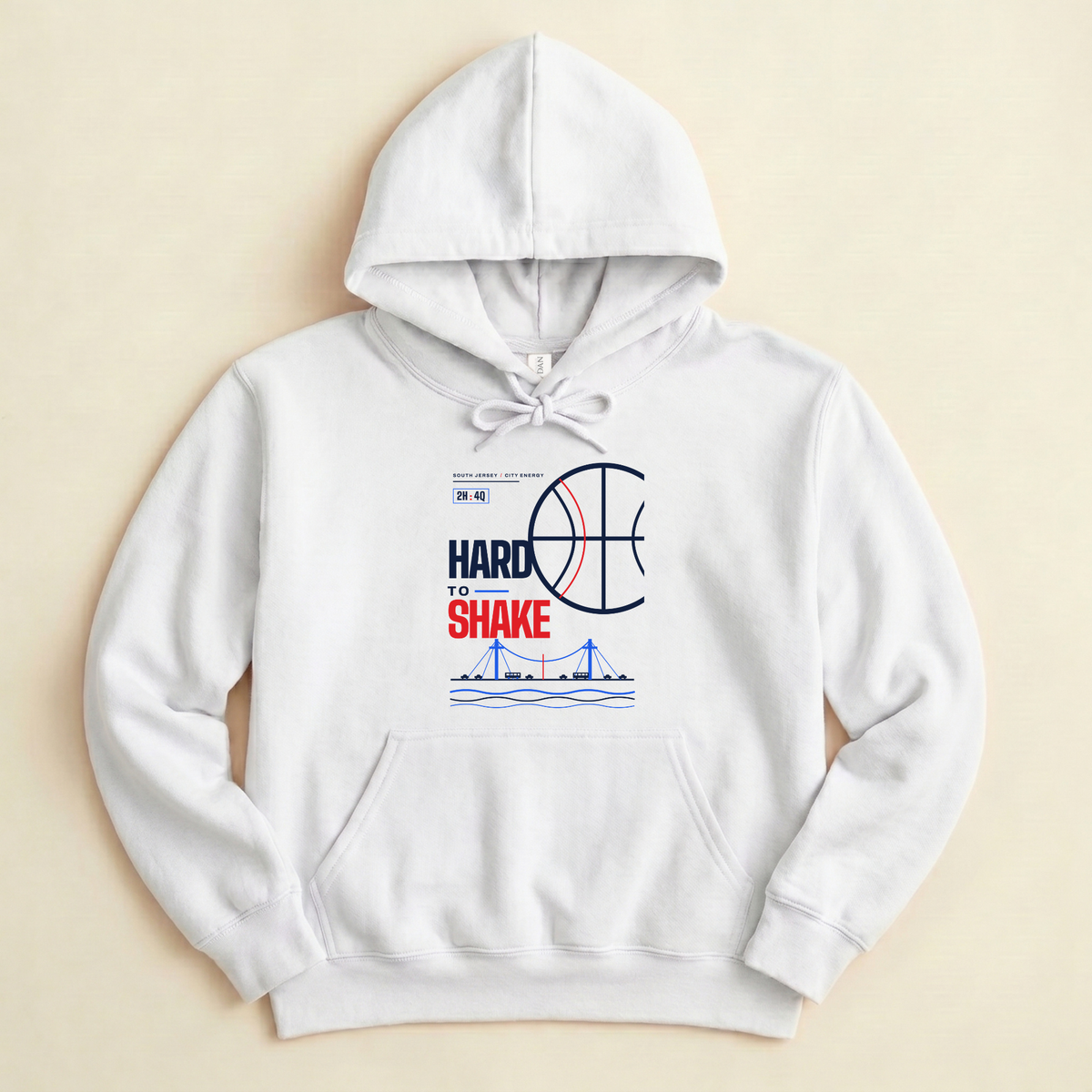 A white pullover hoodie with a graphic print on the front featuring a basketball, the text 'HARD TO SHAKE', and a blue bridge illustration, displayed flat against a light beige background.