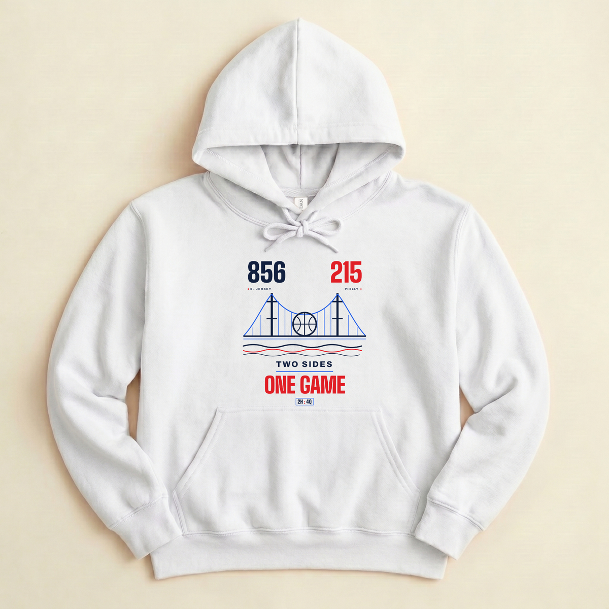 A white pullover hoodie with a front graphic print featuring a bridge illustration and the text '856 215 area codes, TWO SIDES ONE GAME' in blue and red, displayed flat against a light beige background. 
